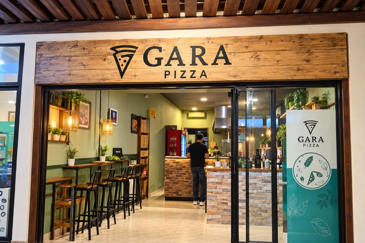 Fachada real da Gara Pizza, com letreiro de madeira, iluminação acolhedora e mesas junto à entrada.